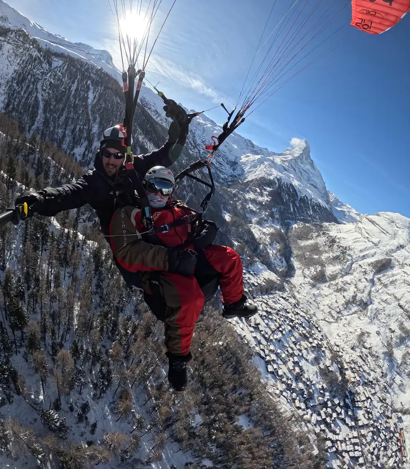 Tandem paraglider soaring above Zermatt with the Matterhorn behind on a Zermatt tour, Switzerland